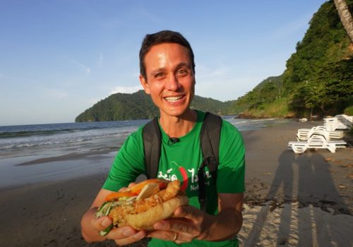 Mark Wiens at Maracas Bay eating Bake and Shark